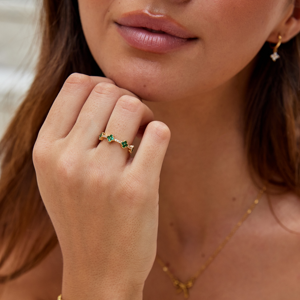 Annika – Guld ring med blomsterdetaljer og smaragd element.